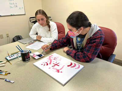 Thayer School of Engineering student working with a braininjury survivor on Unmask the Invisible’s Weighted Paintbrush Program.
